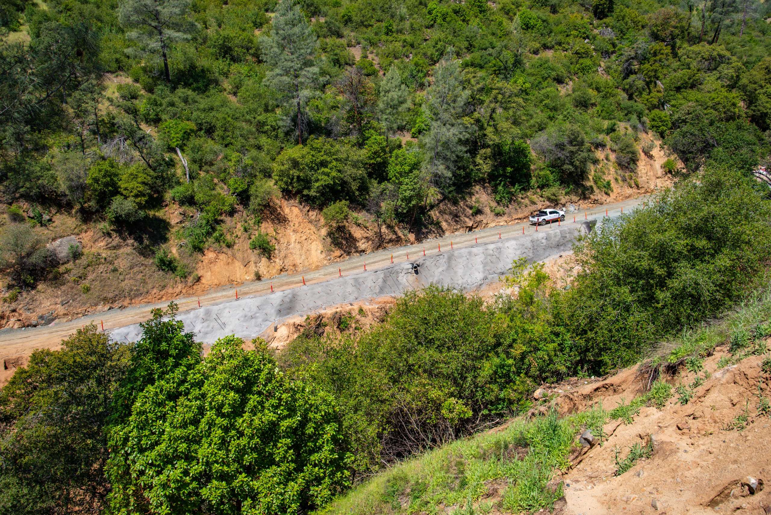 Looking downhill at a gravel road with rocks piled up in the foreground.